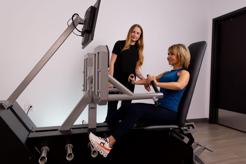female doing chest press on fastfit machine with trainer